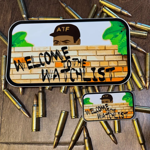 The American Lictor Sticker: Welcome to the Watchlist features a cartoon man in an ATF hat peeking over a brick wall with WELCOME TO THE WATCHLIST text and scattered rifle cartridges. Available in standard dimensions.