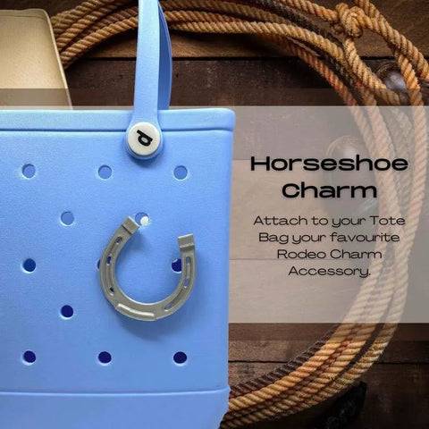 A light blue tote bag with a silver BOGLETS - RODEO Charm by Chatelet Manufacturing, shown on coiled rope. Text: Horseshoe Charm. Personalize your tote with decorative charms from Chatelet Manufacturing to complete your style.