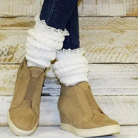 A person wearing Catherine Cole’s LACE Topped Ultimate Slouch Socks in white stands against a rustic wooden background.