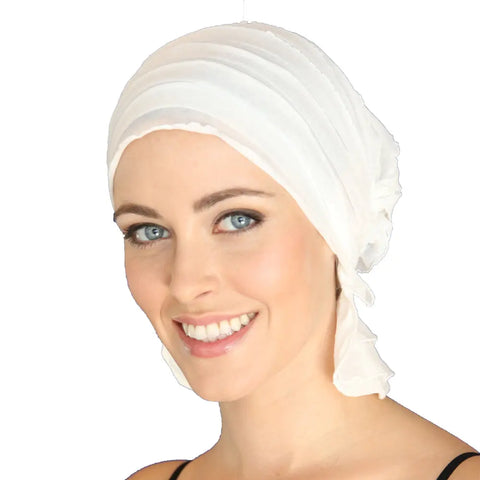 A woman with light skin and blue eyes smiles while wearing the Chemo Beanies® Stella chemo beanie. The white background highlights this stylish hair loss headwear from Chemo Beanies®.
