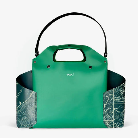 The eqpd WideTote - Methow Map is a modern green handbag with a built-in handle, black strap, and white topographical map sides. The top features the brand logo—ideal as a stylish travel organizer for any adventure.