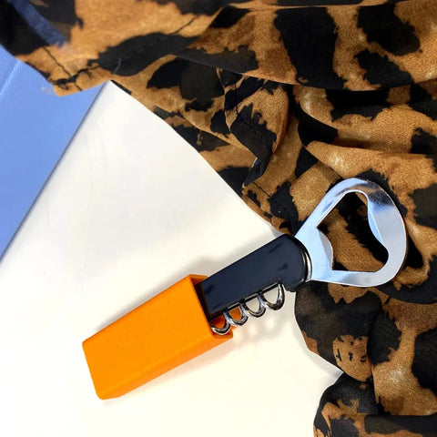 The Chatelet Manufacturing BOGLETS Wine & Bottle Opener Charm Accessory, compatible with Bogg Bags, features a handy corkscrew with an orange handle—perfect for picnics or as a bar tool attachment on your tote.