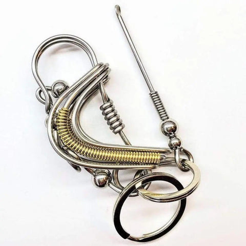 The Wire Coiled Birdie Keychain for Him by Alexa Martha Designs features intertwined silver and gold-toned wire loops, coils, and rings in an abstract, intricate design, resembling a mechanical bird on a white background.