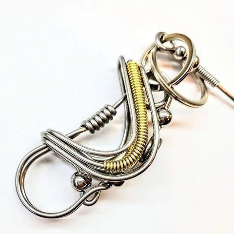 The Wire Coiled Birdie Keychain for Him by Alexa Martha Designs features intricate silver and gold wires coiled into an abstract, artistic form with loops and metallic beads, shown against a plain white background.