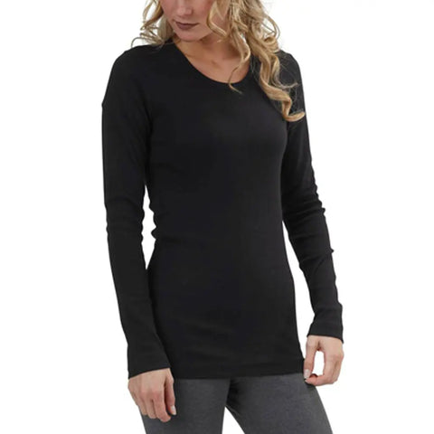 A woman with wavy blonde hair wears the Spiritex Long Sleeve Perfect Crewneck Tee (W), made from organic cotton, paired with gray pants, standing against a white backdrop.