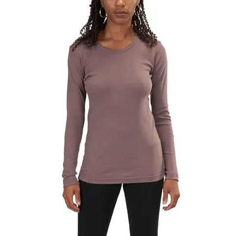 A woman with curly hair models the Spiritex | Sustainable Apparel Long Sleeve Perfect Crewneck Tee (W) in mauve, paired with black pants, standing facing forward against a plain white background.