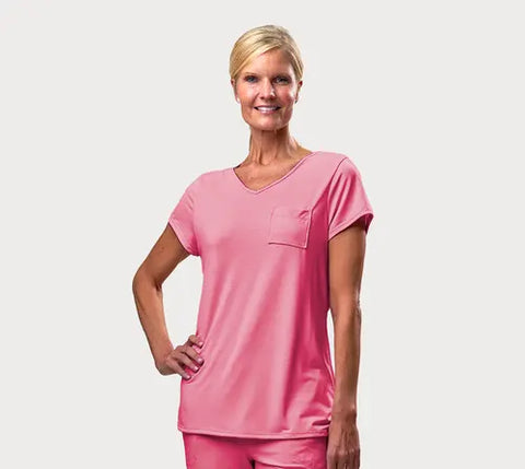 A smiling woman with blonde hair in a low bun wears the Goodnighties Short Sleeve V-Neck Tee and matching moisture-wicking pants, posing with one hand on her hip against a plain white background.
