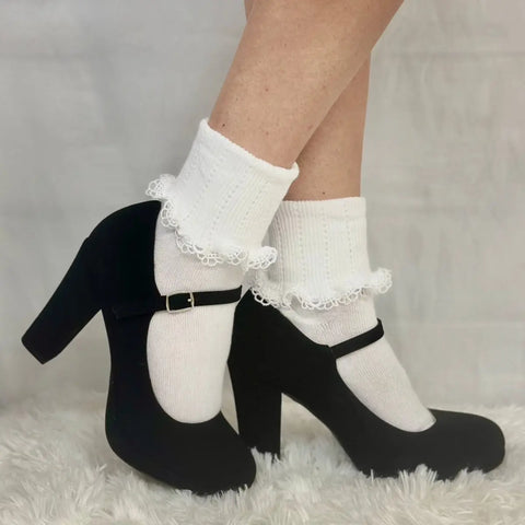A person wears Catherine Cole SCALLOP Cuff Ankle Socks Women - White and black Mary Jane heels, standing on a fluffy white carpet with a neutral background.