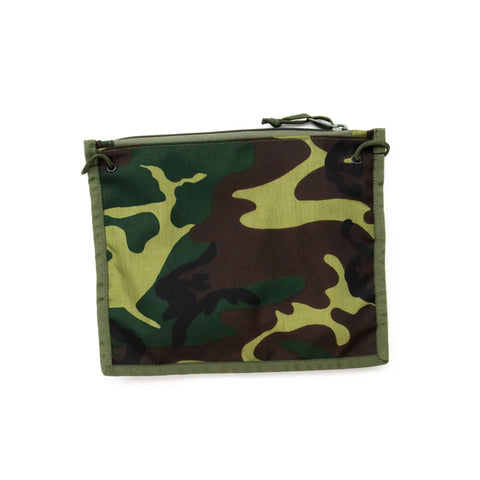 The MIS 2 Way Pouch - Woodland Camo is a rectangular, water-resistant pouch with a green, brown, and black camouflage pattern. It features a top zipper, side drawstring, and is perfect as a tablet clutch against a white background.