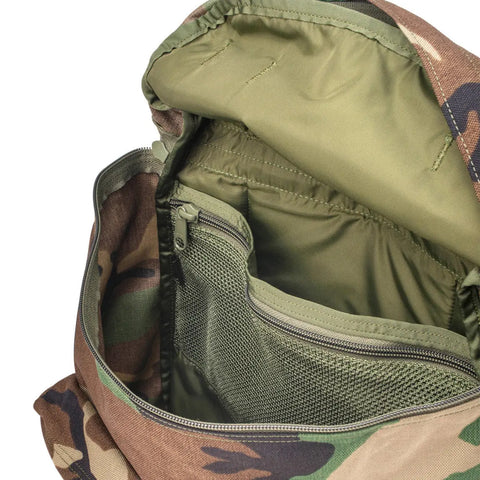 The MIS Backpack - Woodland Camo is open, displaying its green interior, zippered mesh pocket, padded laptop holder, and extra compartments.