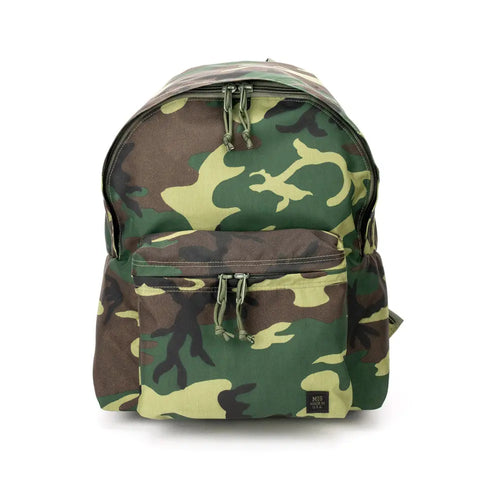 The MIS Daypack - Woodland Camo is a water-resistant nylon backpack in green, brown, and black camouflage, featuring a front zip pocket, black bottom label, zippered main compartment, and upright design.