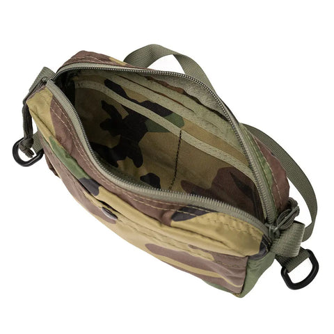 The MIS AW Shoulder Bag S - Woodland Camo is a small packcloth nylon bag with an open zipper showing its empty interior, a green adjustable shoulder strap, and black metal hooks on each end.