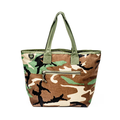 The MIS Tote Bag - Woodland Camo features durable Cordura nylon in green, brown, tan, and black camouflage with green handles and a front zippered pocket, shown against a white background.