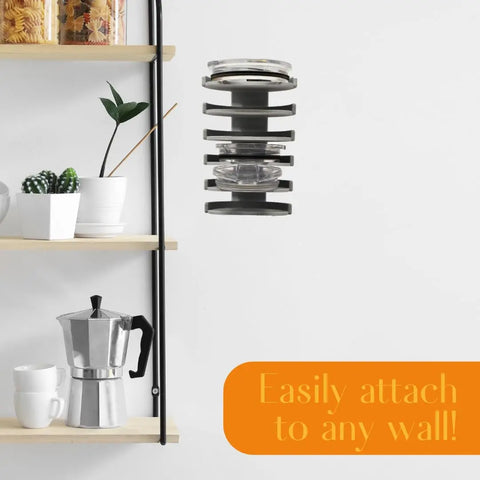 A Yeti Lid Mount Rack by Chatelet Manufacturing is mounted on a white wall beside wooden shelves with a coffee maker, cup, and plants. An orange box reads: Easily attach to any wall! Perfect for kitchen lid storage or as a Lid Organizer Rack.