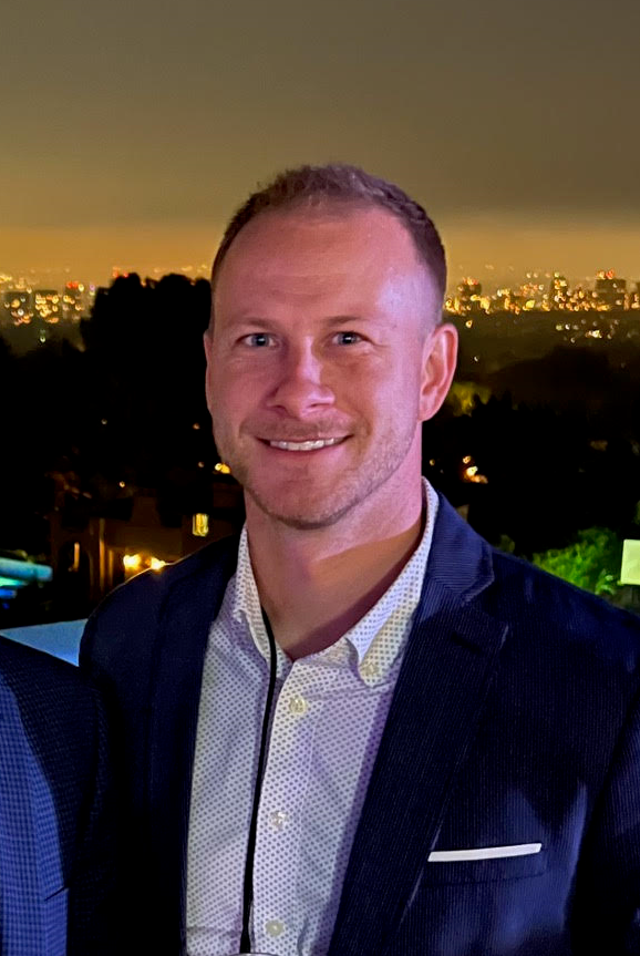 Man in a suit standing in front of a cityscape at night