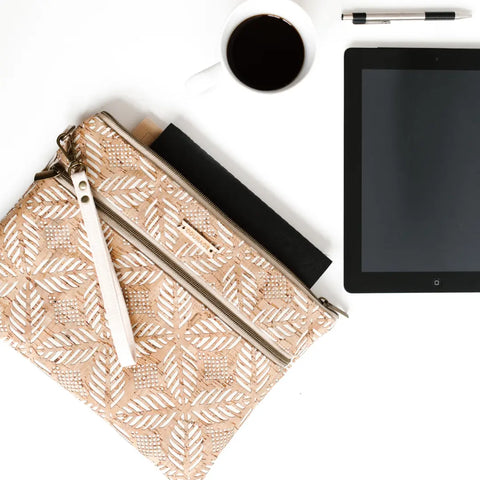 The Carry Courage INVENTOR tablet organizer in cream, a black notebook, a tablet, a cup of black coffee, and a pen are arranged on a white surface.
