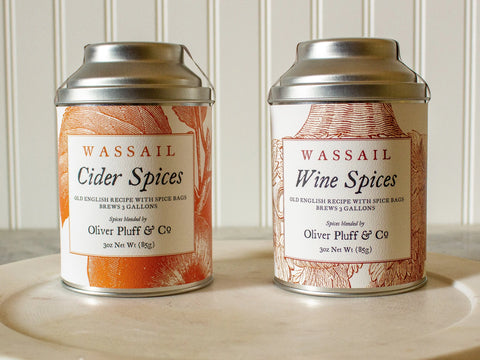 Two tins from Oliver Pluff & Company’s Your Holiday Wassail Kits—Toasting and Tasting—sit side by side, featured as a festive set against a white, vertically paneled background.